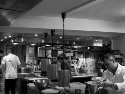 Modern commercial kitchen with stainless steel cooking equipment and an active kitchen line.